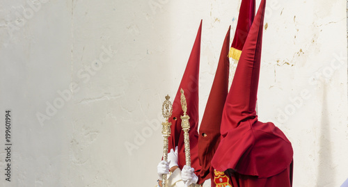 Tableau sur toile Three penitents waiting for the entrance to the temple on Holy Friday in Huelva,