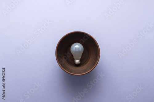 Creative idea - light bulb in brown plate on pastel purple background