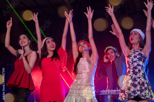 Group of young people celebrate new year party with spot light and fireworks in night party at club. selective focus on women in orange dress. double exposure with bokeh background.