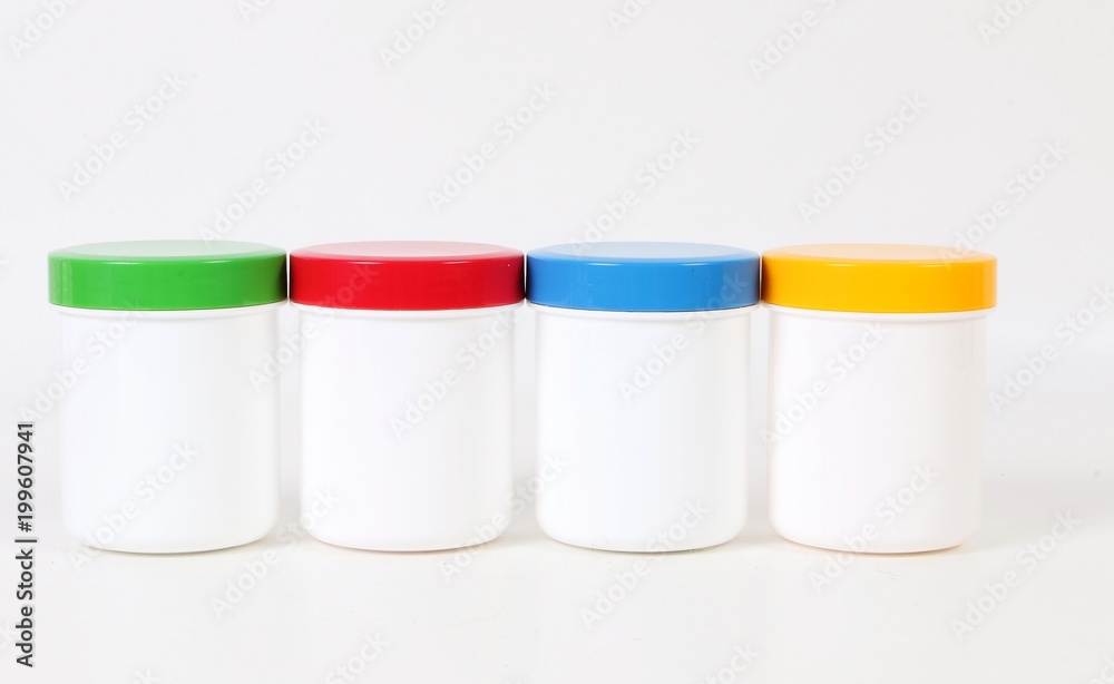 small white plastic tins with colorful caps are standing in the studio in a row small white plastic tins with colorful caps are standing in the studio in a row