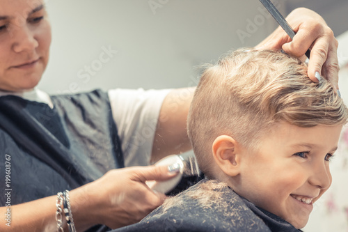 Happy kid getting haircut at hairdresser's.