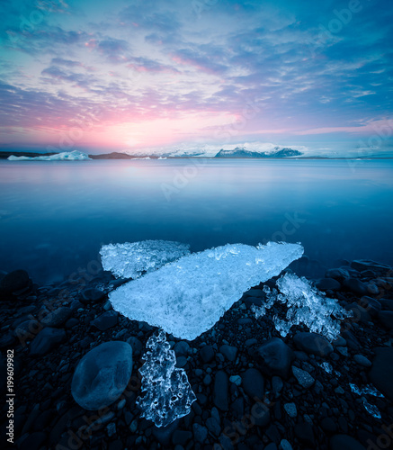 Jokulsarlon glacier lagoon with ice chunks and mountains at beautiful sunset in Iceland