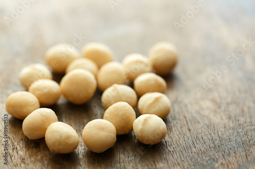A bunch of macadamia nuts scattered on an old wooden brown background, selective focus, copy space