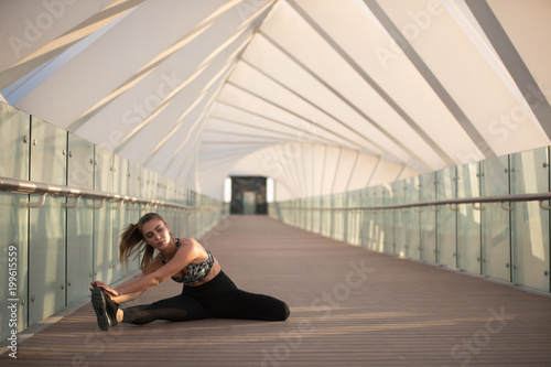 Sports woman doing stretching exercises on a bridge.