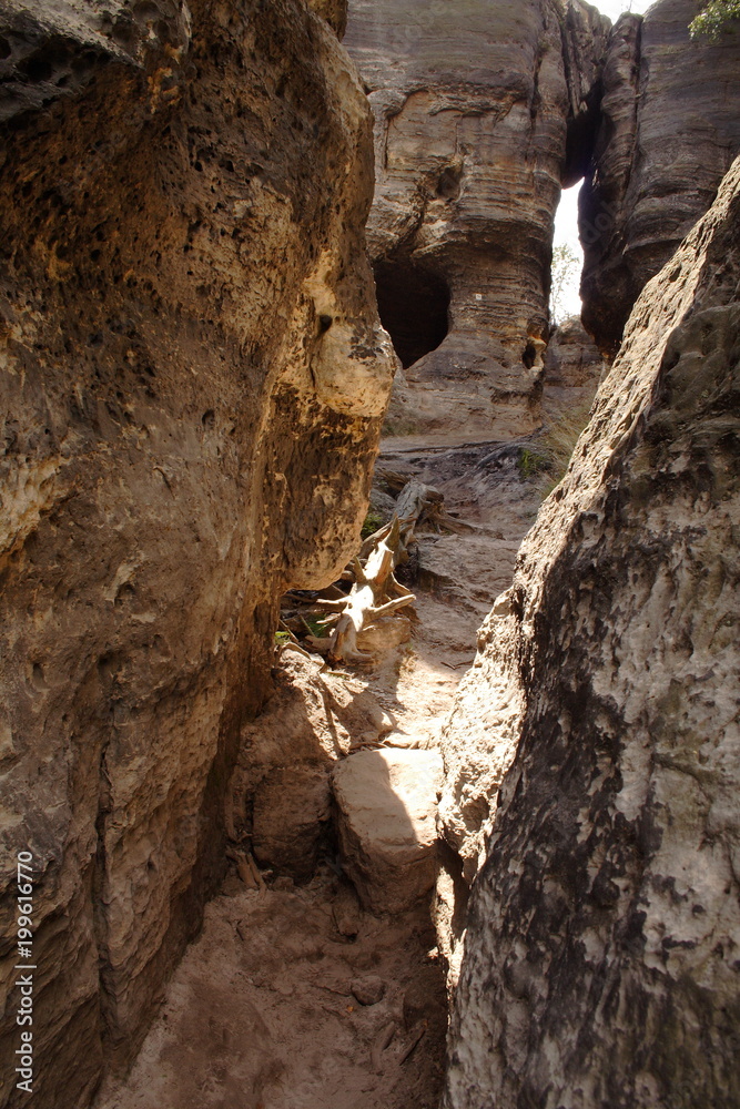 Empty narrow walk way between rock wall.