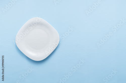 Single empty plate on pastel blue background top view flat lay copy space