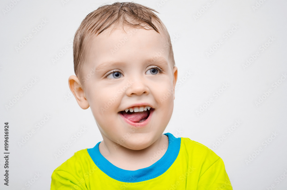 Handsome beautiful little boy teeth smile in a yellow shirt on a light white background Handsome beautiful little boy teeth smile in a yellow shirt on a light white background