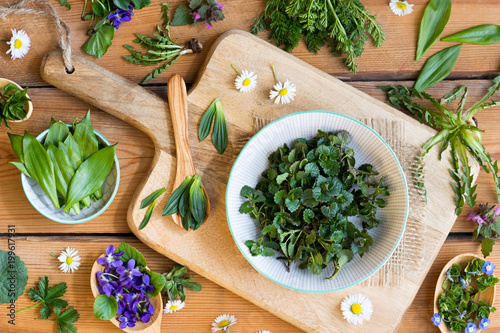 Wild edible spring plants on a wooden table photo
