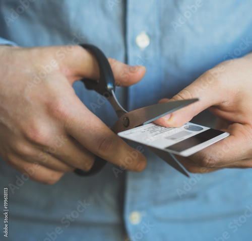 Man cutting credit card with scissors. photo