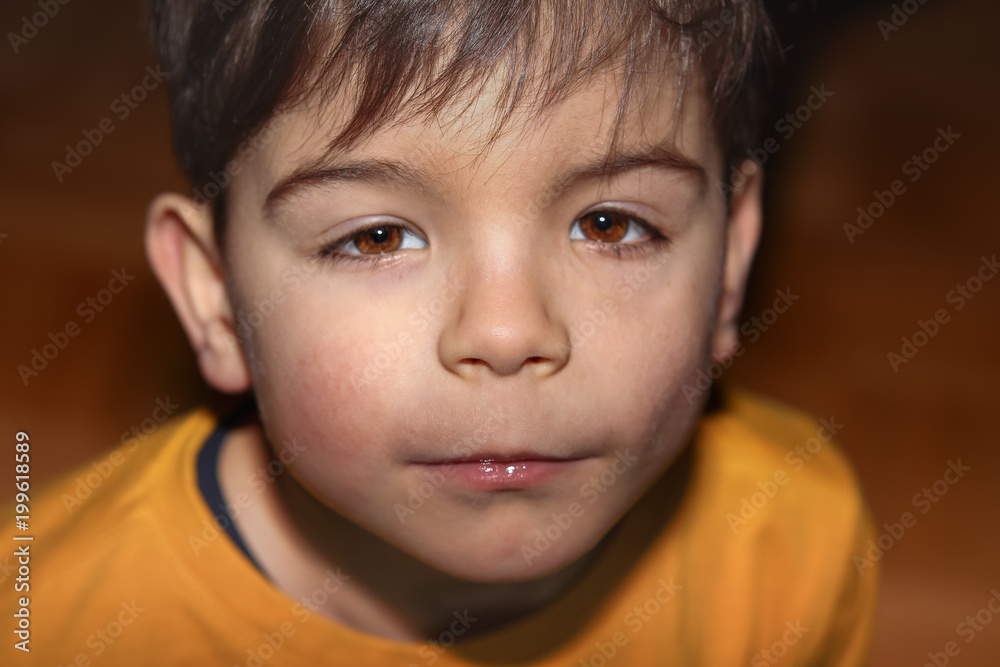 Nahaufnahme eines Jungen im gelben Shirt, der nach oben in die Kamera sieht Nahaufnahme eines Jungen im gelben Shirt, der nach oben in die Kamera sieht