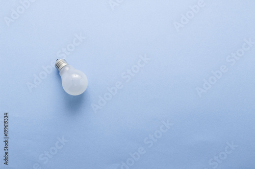 Light bulb on pastel blue background top view, flat lay with copy space