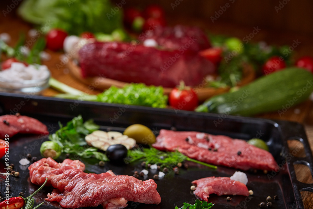 Still life of raw beef meat with vegetables on wooden plate over white background, top view, selective focus Still life of raw beef meat with vegetables on wooden plate over white background, top view, selective focus