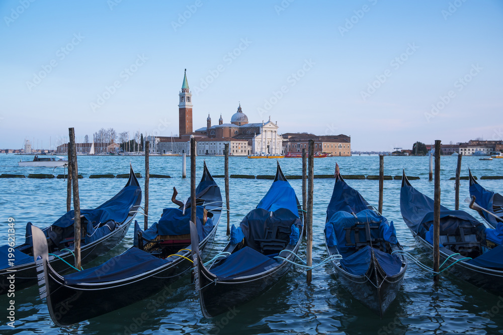 Venice, Italy: gondolas moored in the San Marco basin and the San Giorgio Maggiore church. Italian landscape.
