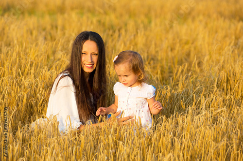 Mom and daughter walking in the grain fields