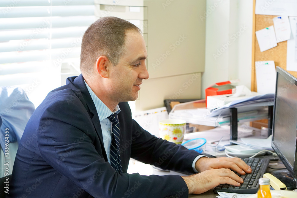 Close-up of office worker. Man Working At Desk In Busy Creative Office. Businessman working at the computer. Close-up of office worker. Man Working At Desk In Busy Creative Office. Businessman working at the computer.