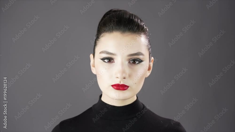 Portrait of a beautiful sexy girl. Fashion model posing on a dark background for studio photo shoot. Slowmo. Close up. Red lips