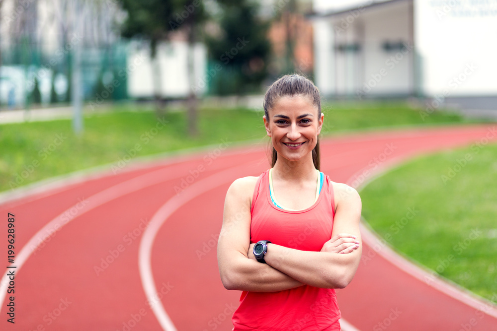 Happy female runner standing with arms crossed