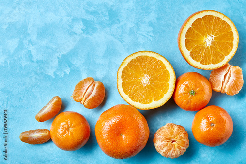 Variety of fresh citrus fruits for making juice or smoothie over blue textured background  top view  selective focus.