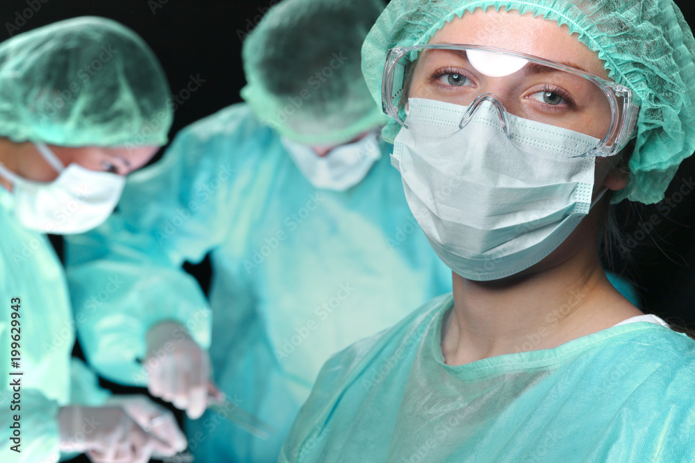 Closeup of surgeons performing operation. Focus on female doctor. Medicine, surgery and emergency help concepts Closeup of surgeons performing operation. Focus on female doctor. Medicine, surgery and emergency help concepts