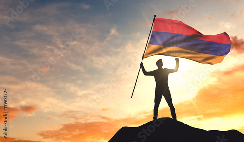 Armenia flag being waved by a man celebrating success at the top of a mountain. 3D Rendering photo
