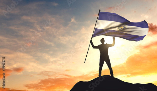 El Salvador flag being waved by a man celebrating success at the top of a mountain. 3D Rendering photo