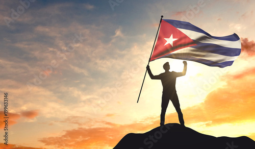 Canvas Print Cuba flag being waved by a man celebrating success at the top of a mountain