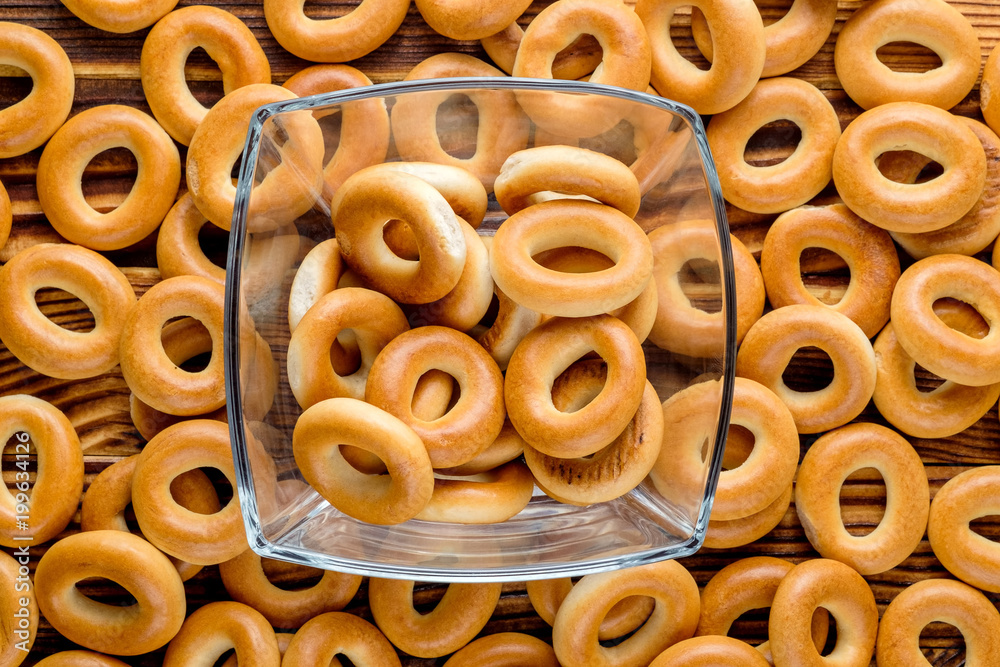 Heap of bagels in glass bowl and on the wooden table. Top view. Heap of bagels in glass bowl and on the wooden table. Top view.