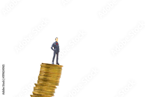 Figure miniature businessman or small people standing on unstable risky stack of coin on white background, money and financial business is not stable concept.