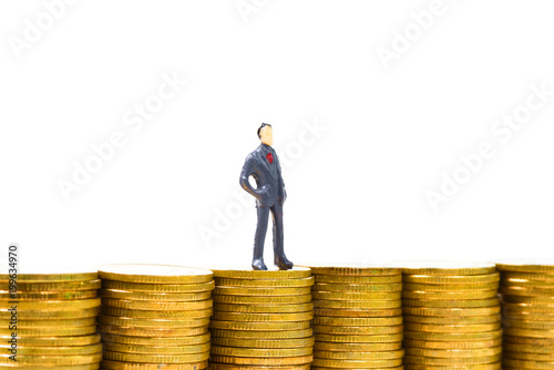 Figure miniature businessman or small people standing on the top stack of coin on white background for money and financial business concept.