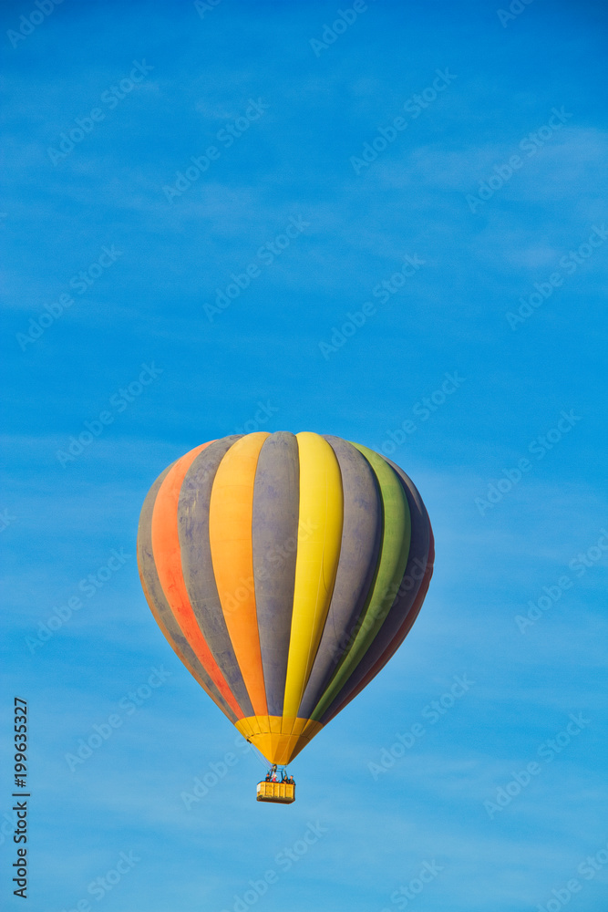 Fototapeta premium A hot air balloon rising under partly cloudy skies.