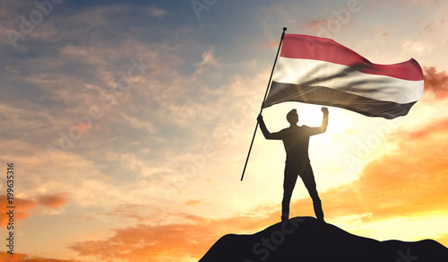 Yemen flag being waved by a man celebrating success at the top of a mountain. 3D Rendering