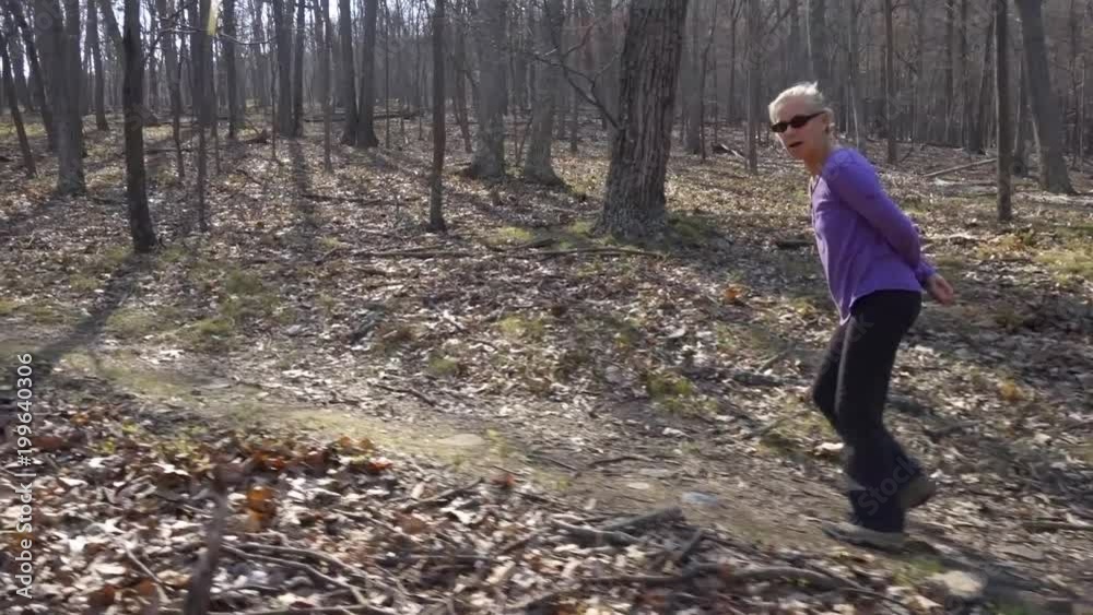 Steadicam shots of mature beautiful woman hiking through a forest on the brink of spring.