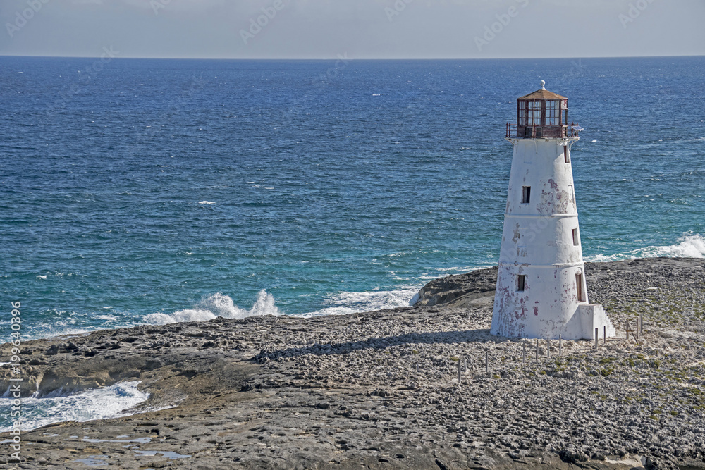 Old abandoned lighthouse beside blue water in the Bahamas.