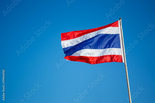 Photograph of national Thai flag in the blue sky background.
