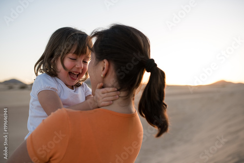 Happy daughter hugging with her mother on sand dune