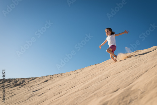 Girl running down sand dune