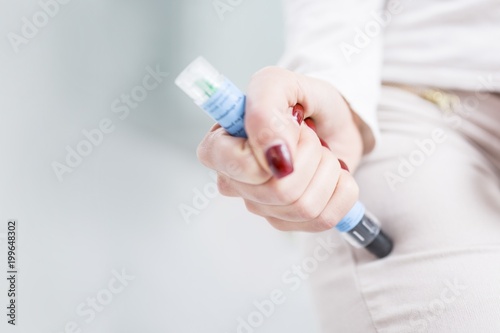 Woman injecting herself in the thigh photo