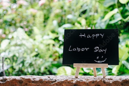 Happy labor day greeting card concept, Chalk board with text HAPPY LABOR DAY with green fresh garden background