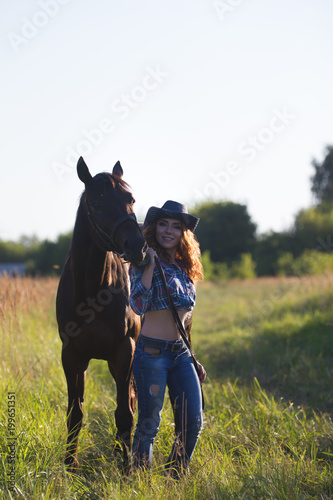 Young attractive woman and horse in the meadow at summer evening