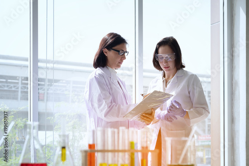 Young female scientist standing with teacher in lab worker making medical research in modern laboratory.