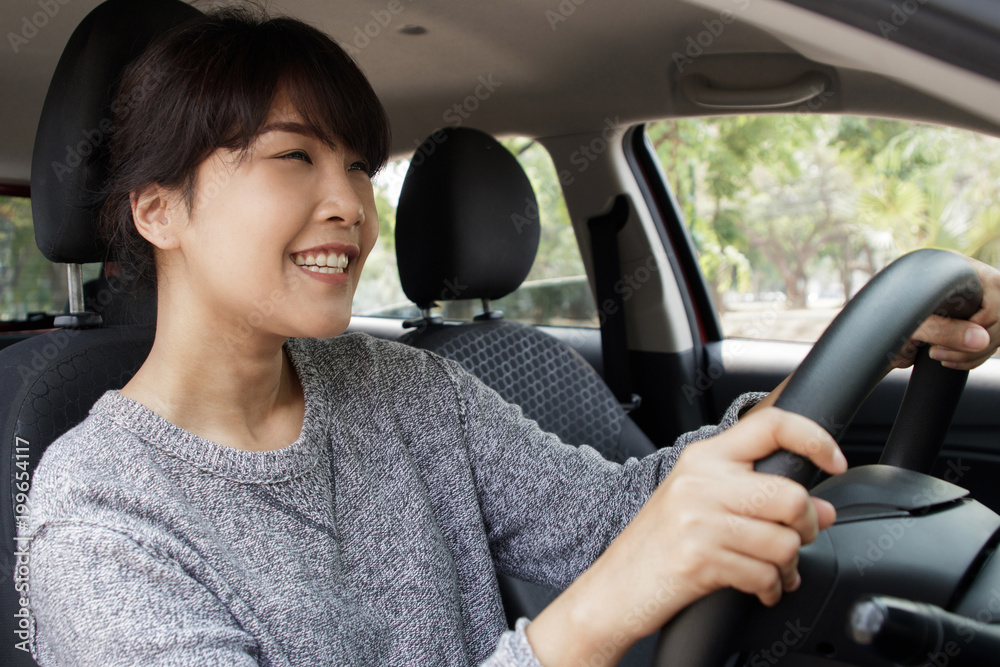 Young asian woman in casual wear driving a car and smiling. Confident and beautiful. Young asian woman in casual wear driving a car and smiling. Confident and beautiful.