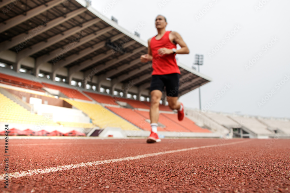 Sport Background. Runner. Athletic man running on stadium track. Selective focus.
