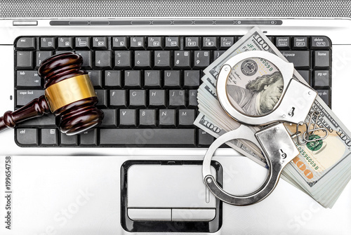 Gavel, handcuffs and money on the laptop keyboard. Close up. Top view.