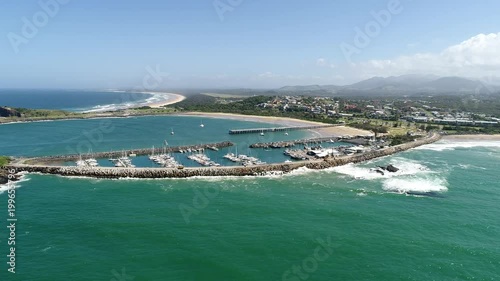 Coffs Harbour protected yacht and boats marina behind wave break wall connected to Muttonbird island in aerial panning.
 photo