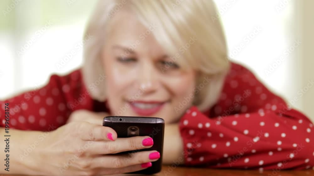 Attractive blond woman messaging on her cell phone. Camera rack focuses from the phone to the woman's face. Attractive blond woman messaging on her cell phone. Camera rack focuses from the phone to the woman's face.