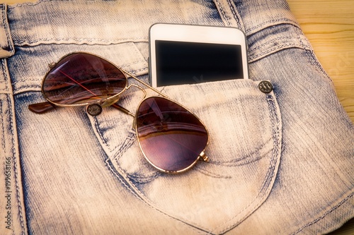 Blue short jeans with cell phone and sunglasses in the pocket