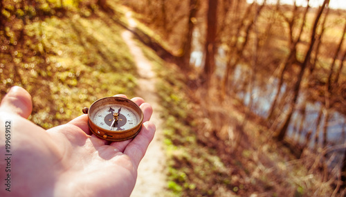 Traveler holds a compass in his hand, traveling around the world, looking for a road, close-up