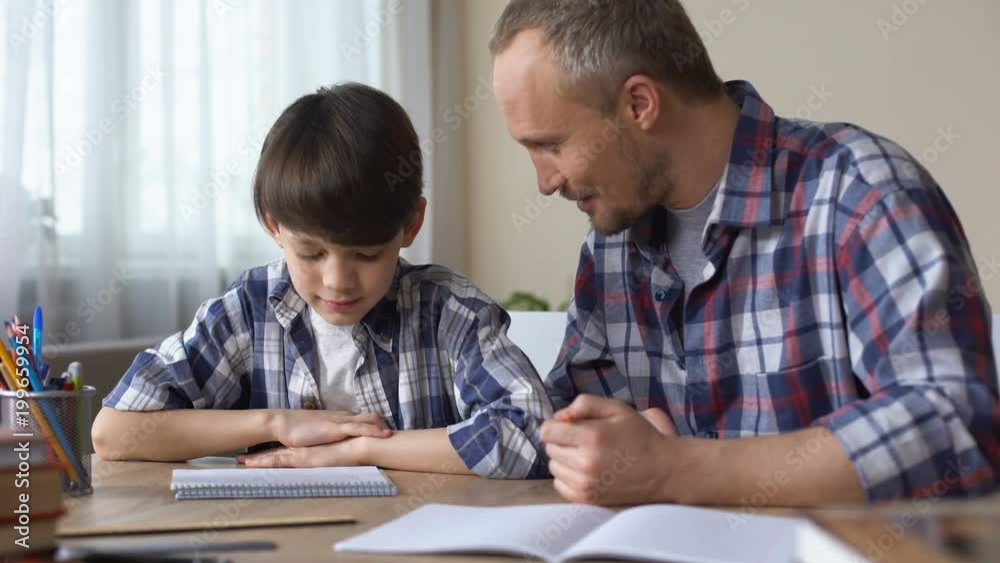 Son and father doing homework together, giving high five each other, teamwork Son and father doing homework together, giving high five each other, teamwork
