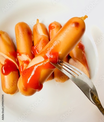 Sausage topped with tomato sauce on a white plate. photo