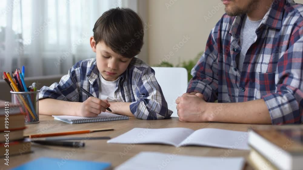 Bored little boy doing homework with strict father, sad child looking in window Bored little boy doing homework with strict father, sad child looking in window